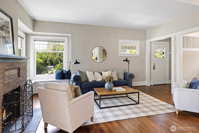 living area with a brick fireplace, wood finished floors, and baseboards