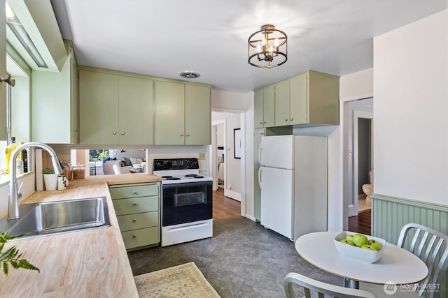 kitchen with white appliances, a sink, light countertops, green cabinetry, and a chandelier