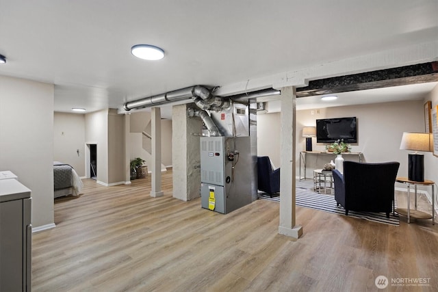 finished basement with heating unit, wood finished floors, and baseboards
