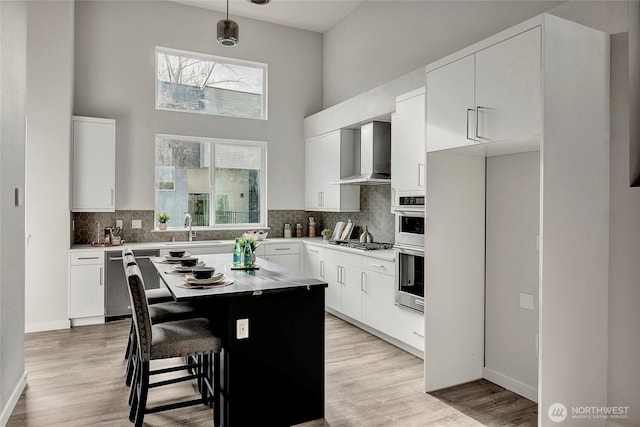8826 NE 173rd Pl Unit B, Bothell, WA 98011 - kitchen featuring wall chimney range hood, stainless steel appliances, a sink, a high ceiling, and backsplash