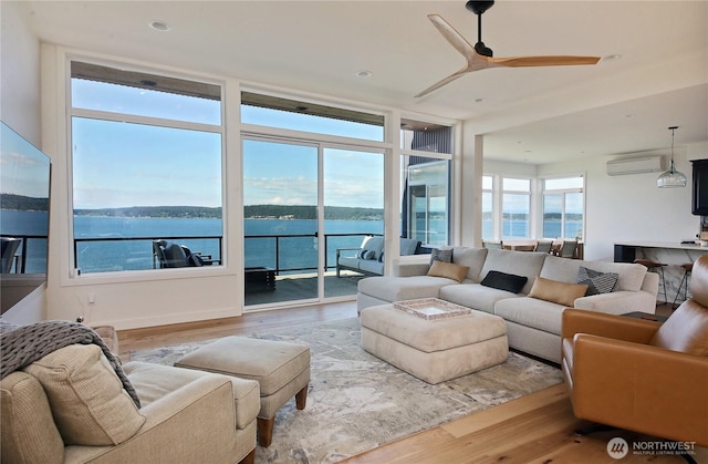 3139 Saratoga Rd, Langley, WA 98260 - living area with an AC wall unit, wood finished floors, a water view, a ceiling fan, and a wall of windows