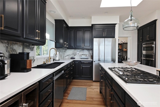 3139 Saratoga Rd, Langley, WA 98260 - kitchen with stainless steel appliances, light wood-style floors, a skylight, dark cabinets, and light countertops