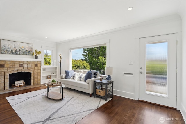 living area featuring dark wood-style flooring, a fireplace, ornamental molding, recessed lighting, and baseboards