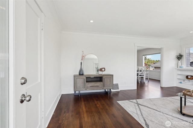 foyer with dark wood finished floors, crown molding, and baseboards