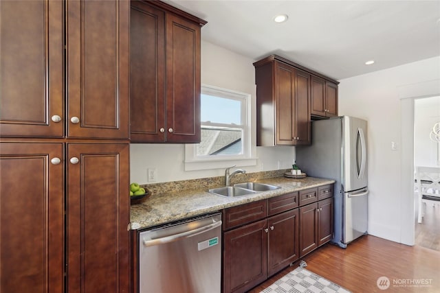 kitchen featuring stainless steel appliances, a sink, wood finished floors, and recessed lighting