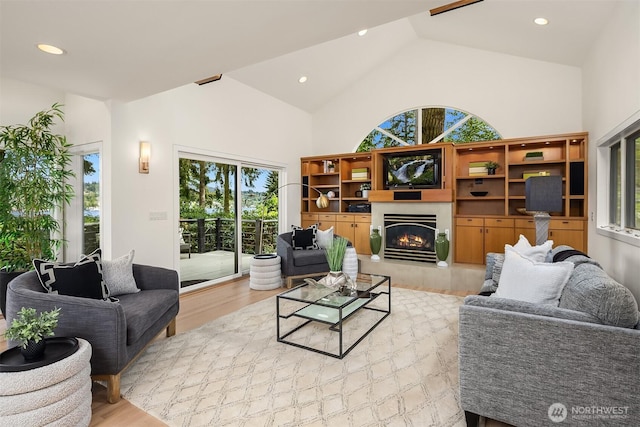 living area with light wood finished floors, high vaulted ceiling, a tile fireplace, and recessed lighting