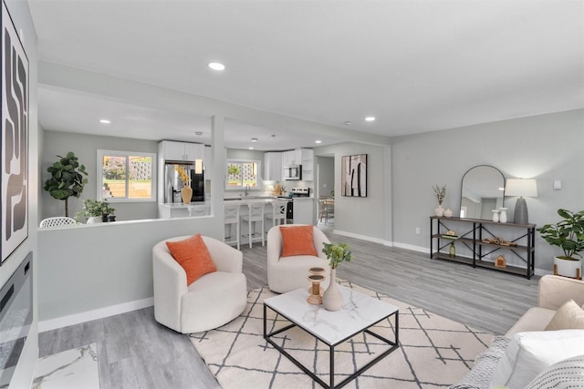 living area featuring light wood finished floors, baseboards, and recessed lighting