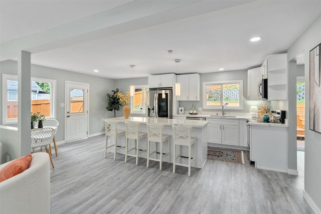 kitchen with stainless steel appliances, a sink, baseboards, light wood-style floors, and recessed lighting