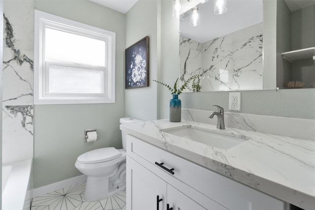 bathroom with toilet, vanity, baseboards, and a tub