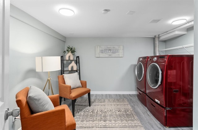 clothes washing area featuring washer and clothes dryer, wood finished floors, and baseboards