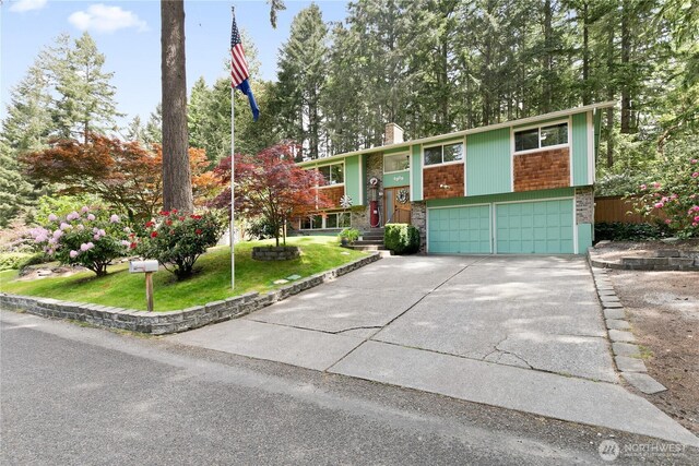 4909 95th Ave W, University Place, WA 98467 - raised ranch featuring a garage, concrete driveway, a front yard, a chimney, and brick siding