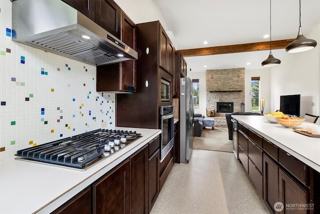 kitchen featuring extractor fan, stainless steel appliances, open floor plan, light countertops, and a stone fireplace
