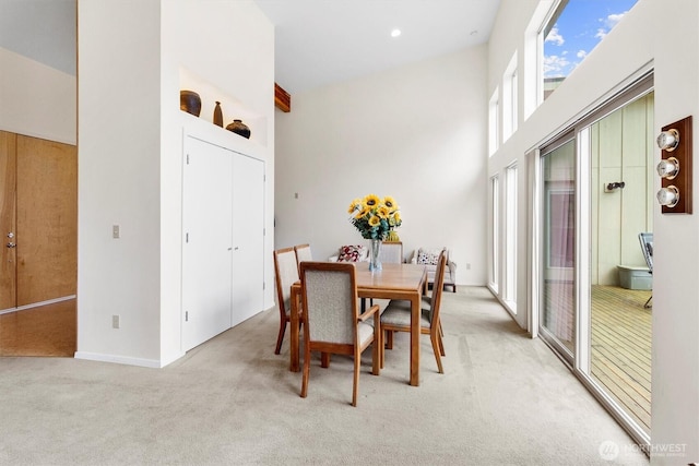 dining space featuring light colored carpet and a high ceiling