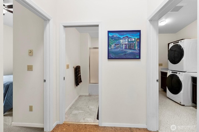 clothes washing area featuring stacked washer / drying machine and baseboards