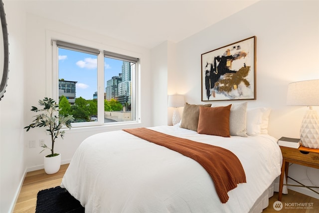 2721 1st Ave Unit 407, Seattle, WA 98121 - bedroom featuring wood finished floors, baseboards, and a city view