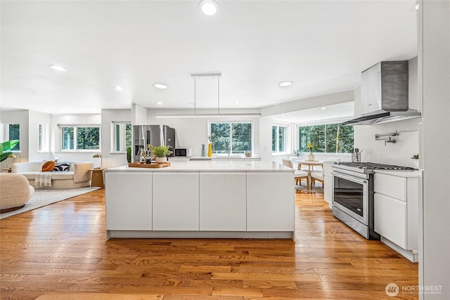 27923 NE 49th St, Redmond, WA 98053 - kitchen with appliances with stainless steel finishes, wall chimney range hood, light wood-style floors, a kitchen island, and white cabinets