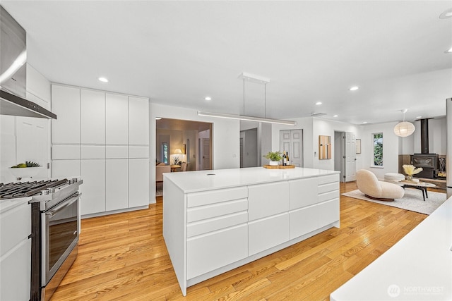 27923 NE 49th St, Redmond, WA 98053 - kitchen featuring gas range, wall chimney exhaust hood, modern cabinets, a wood stove, and light wood finished floors