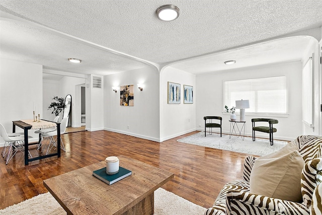 9819 Park Ave S, Tacoma, WA 98444 - living room featuring arched walkways, wood finished floors, a textured ceiling, and baseboards