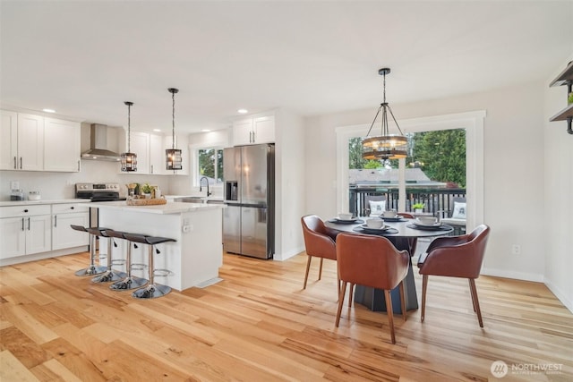 429 217th Pl SW, Bothell, WA 98021 - kitchen with appliances with stainless steel finishes, wall chimney range hood, light wood-type flooring, white cabinets, and healthy amount of natural light
