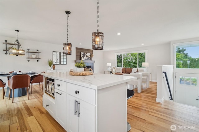 429 217th Pl SW, Bothell, WA 98021 - kitchen featuring stainless steel microwave, light wood finished floors, a kitchen island, white cabinetry, and recessed lighting