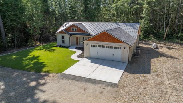 2075 NW Peterson Rd, Poulsbo, WA 98370 - view of front facade with concrete driveway, a garage, a wooded view, and a front yard