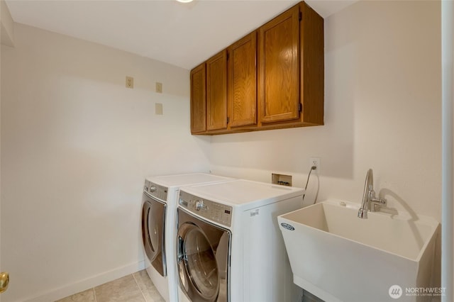 washroom featuring cabinet space, washing machine and clothes dryer, light tile patterned floors, and baseboards