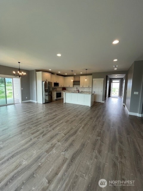 9 Columbia View Dr, Brewster, WA 98812 - unfurnished living room with recessed lighting, a chandelier, baseboards, dark wood-type flooring, and healthy amount of natural light
