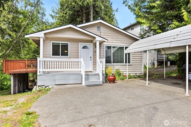 bungalow-style house featuring a carport, asphalt driveway, and a porch