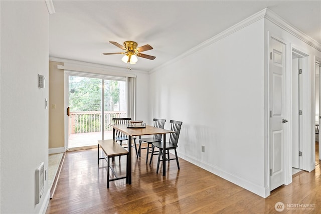 dining room with a ceiling fan, wood finished floors, baseboards, and ornamental molding
