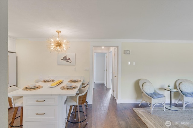dining room with dark wood-style floors, baseboards, a chandelier, and ornamental molding
