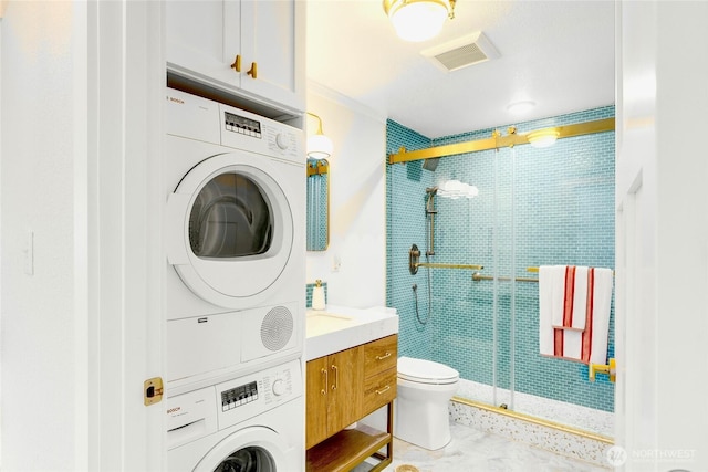 full bathroom with stacked washer / dryer, a shower stall, toilet, vanity, and ornamental molding