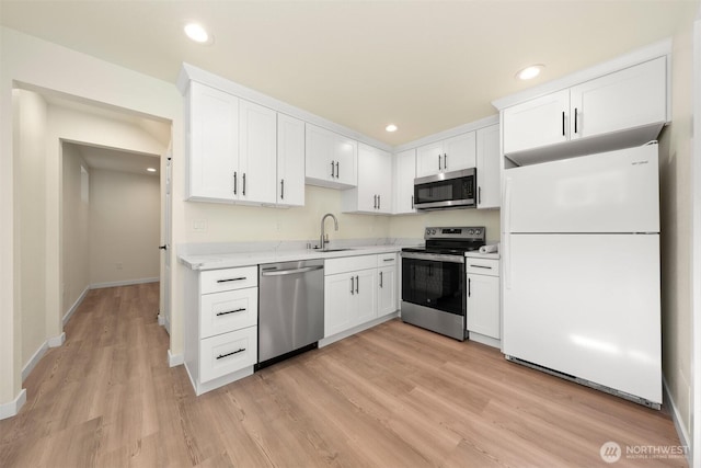 8322 Wabash Ave S, Seattle, WA 98118 - kitchen featuring stainless steel appliances, white cabinetry, light wood finished floors, baseboards, and recessed lighting