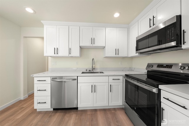 8322 Wabash Ave S, Seattle, WA 98118 - kitchen featuring appliances with stainless steel finishes, a sink, light wood-style flooring, baseboards, and white cabinetry