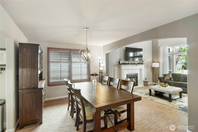dining area featuring a fireplace, a chandelier, baseboards, and arched walkways