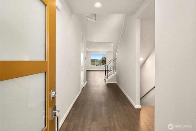 corridor featuring wood finished floors, baseboards, recessed lighting, and stairway