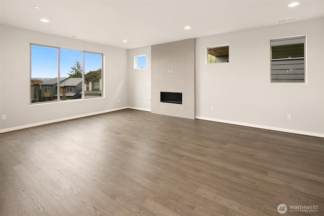 unfurnished living room featuring dark wood-style flooring, recessed lighting, baseboards, and a fireplace