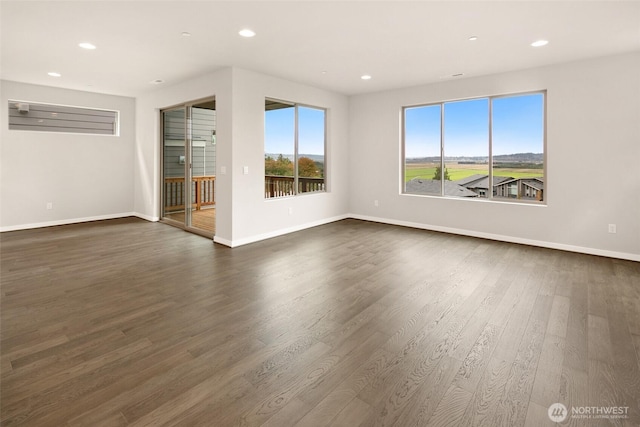 empty room featuring dark wood-style flooring, recessed lighting, and baseboards