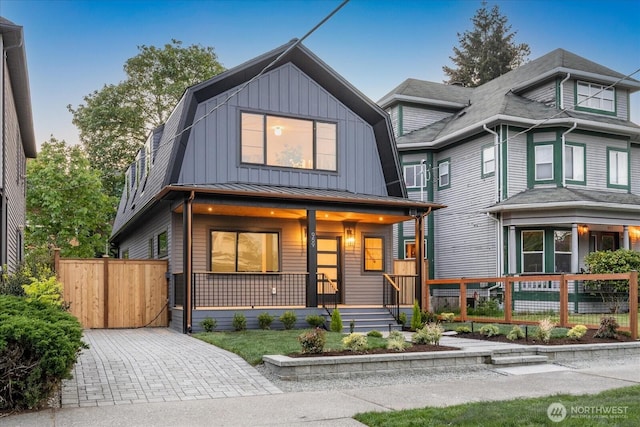 view of front of home with a porch, board and batten siding, fence, a standing seam roof, and metal roof