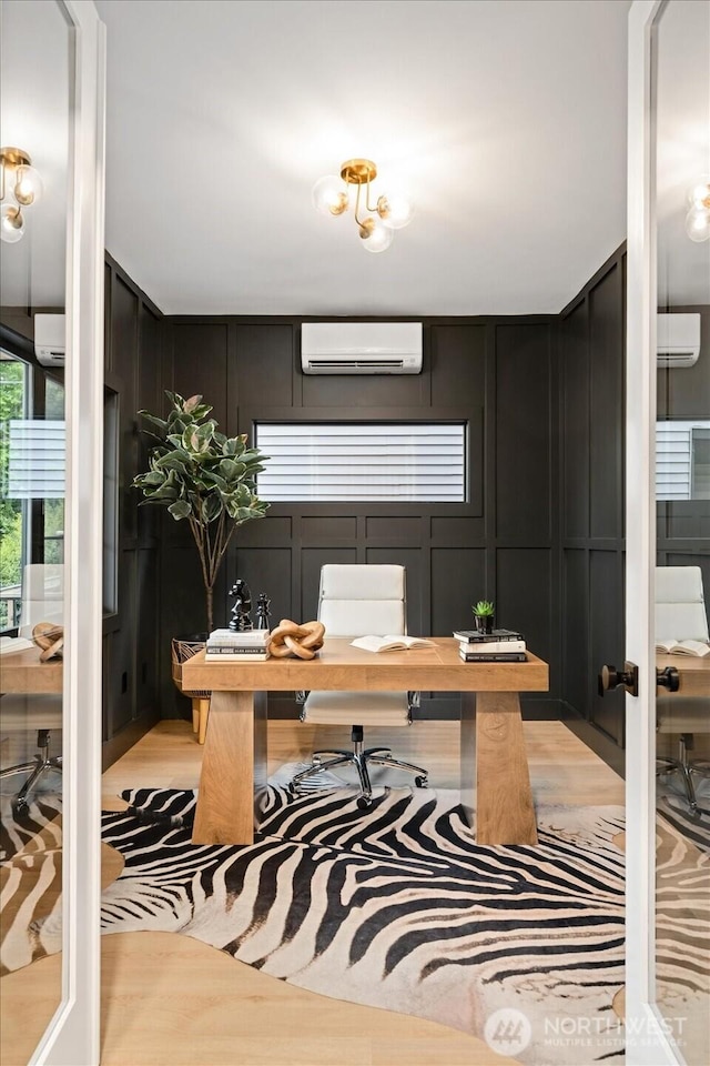 home office with a decorative wall, a wall mounted AC, and light wood-style floors
