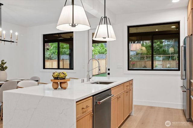 kitchen with a sink, stainless steel appliances, light wood-style flooring, light brown cabinets, and a chandelier
