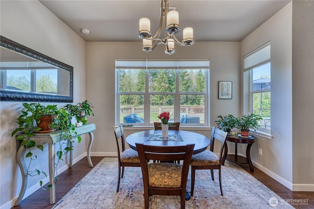 dining space with baseboards, a chandelier, and wood finished floors