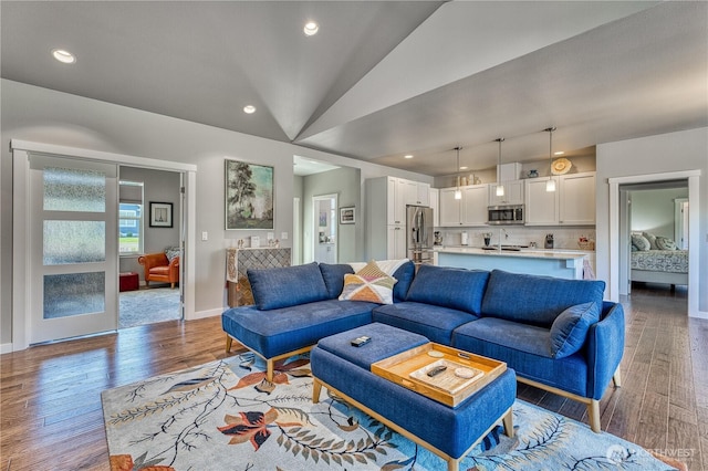 living room featuring vaulted ceiling, wood finished floors, baseboards, and recessed lighting