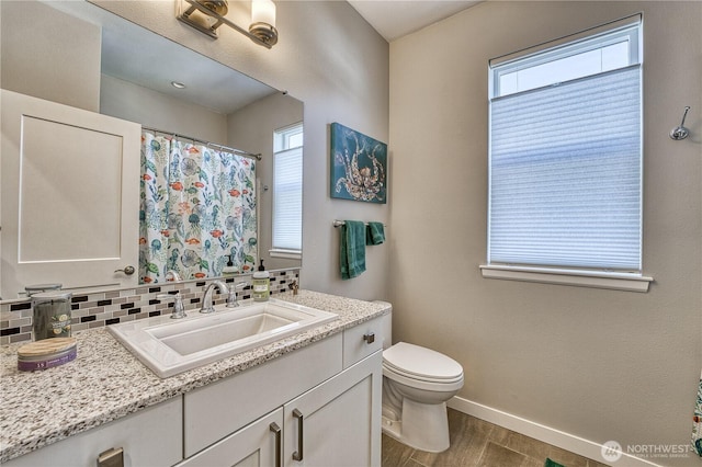 full bath featuring backsplash, baseboards, wood finished floors, toilet, and vanity