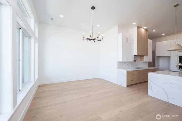 6773 Rd E.2 NE, Moses Lake, WA 98837 - kitchen with modern cabinets, a sink, a chandelier, light wood-style flooring, and decorative backsplash