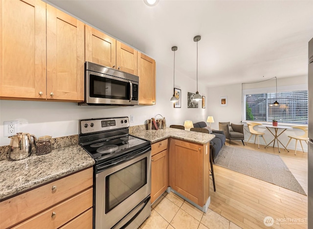 kitchen featuring stainless steel appliances, light brown cabinets, open floor plan, a peninsula, and light stone countertops