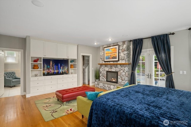 bedroom with access to exterior, light wood finished floors, and a fireplace