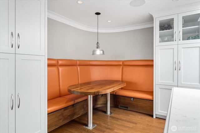 dining space with crown molding, light wood finished floors, wainscoting, and breakfast area