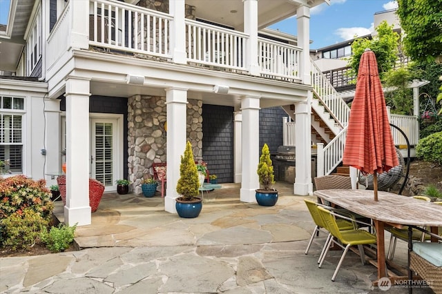view of patio featuring outdoor dining space, a balcony, stairway, and a grill