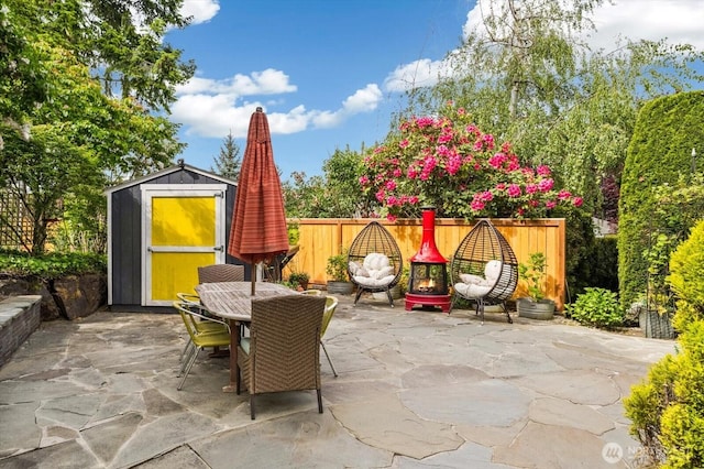 view of patio / terrace with a storage shed, an outbuilding, outdoor dining space, and a fenced backyard