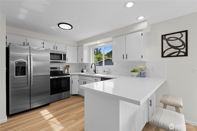 8716 Main St, Edmonds, WA 98026 - kitchen with appliances with stainless steel finishes, a peninsula, light wood-type flooring, light countertops, and recessed lighting